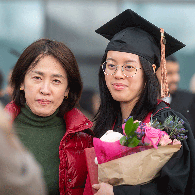A female graduate poses with a loved one after commencement.