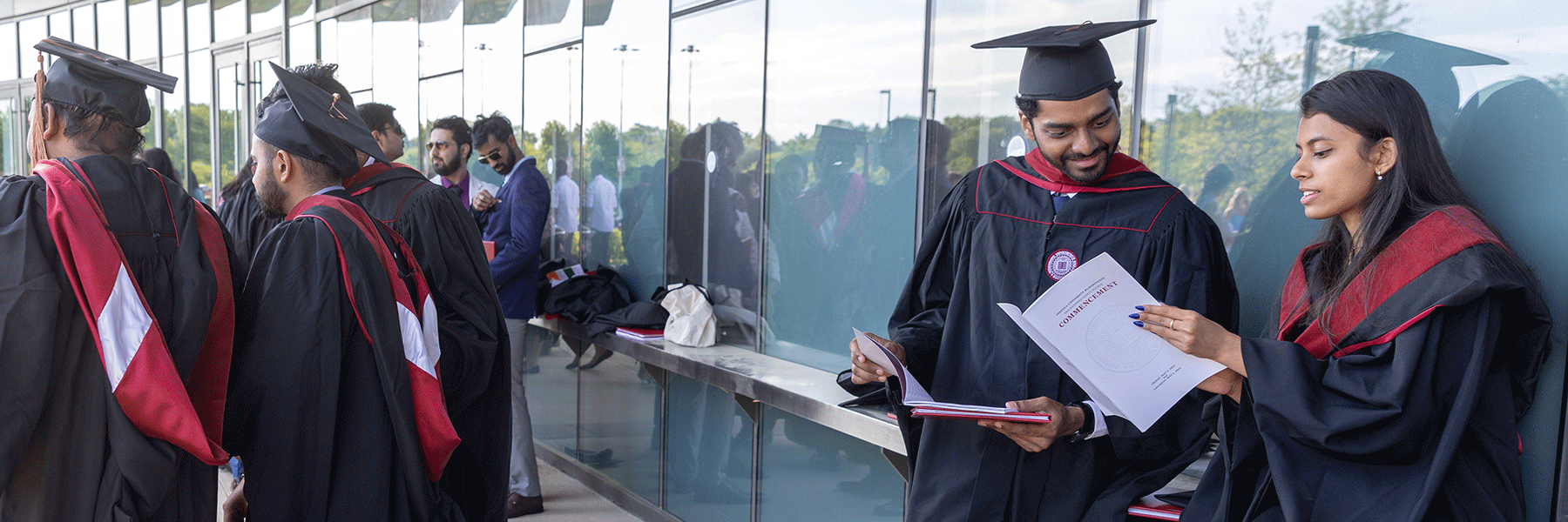 Graduates read the ceremony program while waiting to line up.