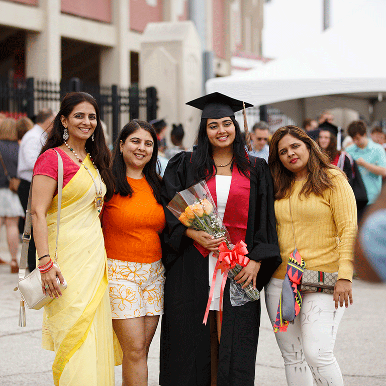 A graduate holding roses poses with their family.
