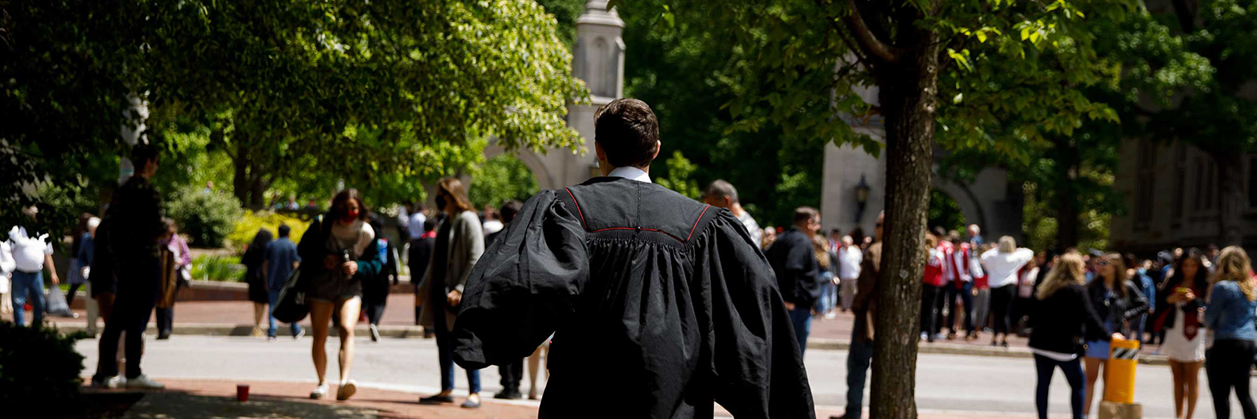 A young graduate runs towards the Sample Gates, his graduation robe billowing behind him. 