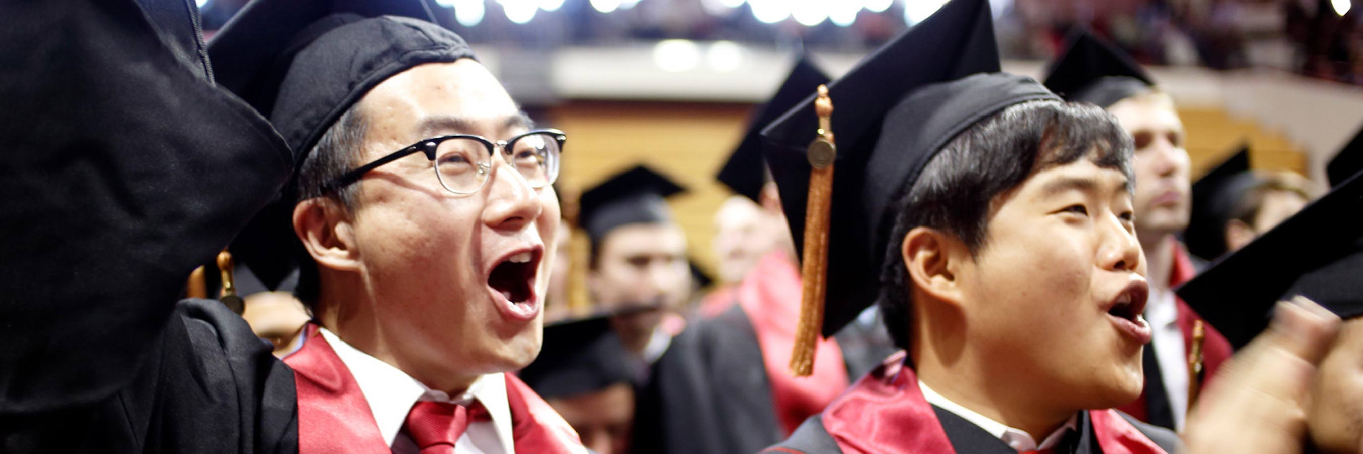 Two male students cheer uproariously at graduation